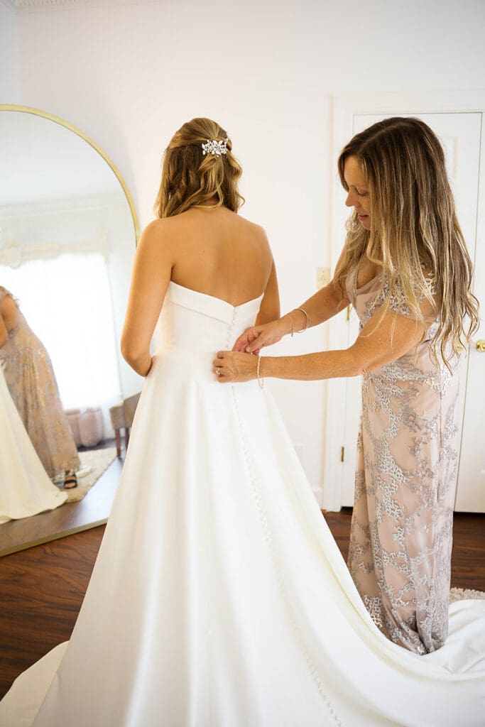 mother of the bride helping her with her wedding dress