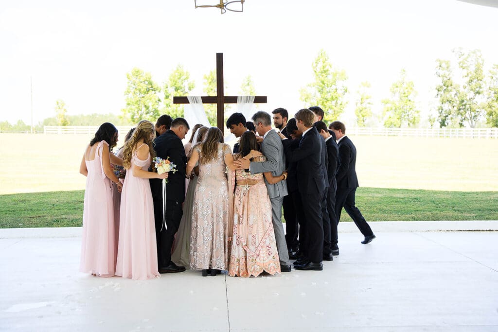 family and friends praying over the bride and groom during their ceremony