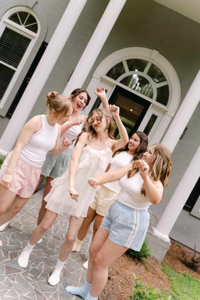 bridesmaids laughing and dancing outside the house on the wedding morning