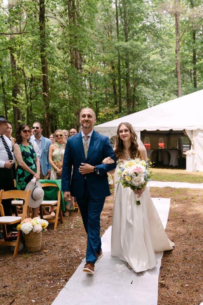 bride walking down the white aisle on her father's arm at a forest wedding in Georgia
